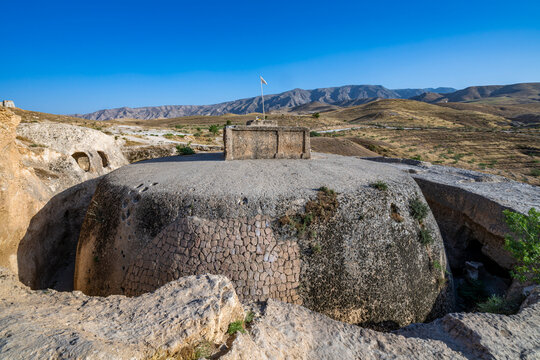 Giant stupa carved in rock stands tall under the clear sky in Samangan