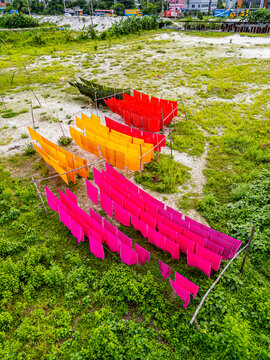 Freshly dyed cloths hanging in bright colors in Araihazar village, Bangladesh near a grassy area
