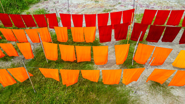 Freshly dyed cloths hang to dry under the sunlight in a village setting