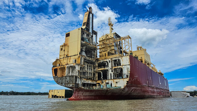 Shipwreck cemetery in Chittagong shows remains of large vessels at high tide under a bright sky