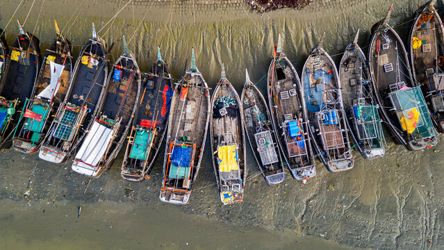 View of the fish market with boats moored along the shore during the early morning in Chittagong, Bangladesh