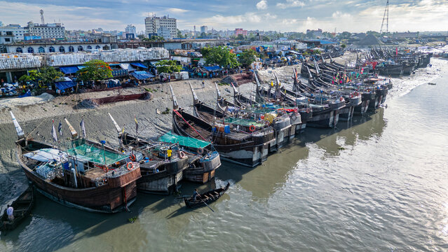 Boats anchor at fish market on Karnaphuli River in Chittagong, Bangladesh with buildings and docks nearby