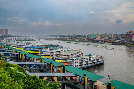 Ferry terminal view showing boats and river activity during a cloudy day in Dhaka, Bangladesh