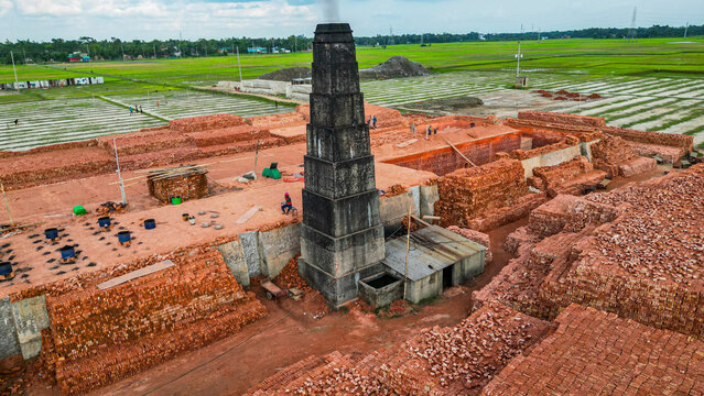 Brick production process at a facility surrounded by fields in Bangladesh during daylight hours