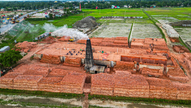 Brick factory operates in rural area with smoke rising from chimney in Dhaka Bangladesh