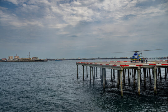 Helicopter lands on platform in the largest oil city, showcasing activity in Neft, Azerbaijan with industrial backdrop