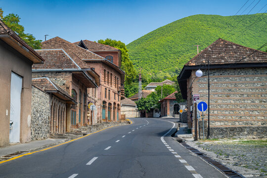 Explore the old city with winding roads and historic buildings set against the mountain backdrop in Sheki, Azerbaijan