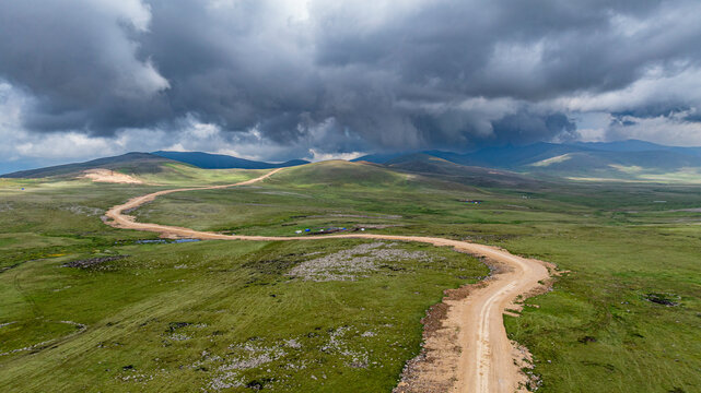 Highland view of Qarabaqh showing winding roads and vast green fields under cloudy skies in Azerbaijan