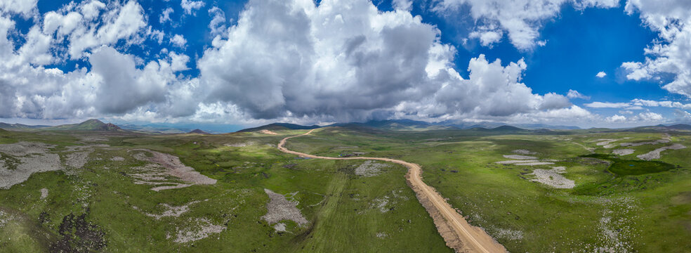 Highland scenery captures open landscape with clouds and dirt path in Qarabaqh, Azerbaijan