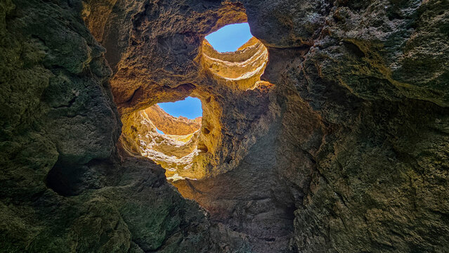 Seacave with rock formations and openings showcasing bright sky in Carvoeiro, Algarve Portugal