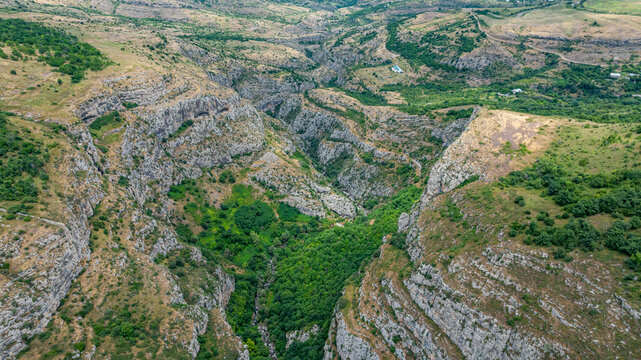 Aerial view of a large canyon with steep cliffs and green vegetation in Qarabaqh region, Azerbaijan during daylight hours