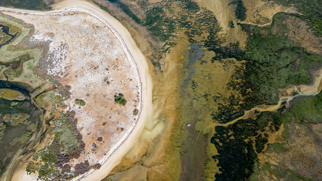 Wetlands surround the coastal area with sand and water near Olhao in Algarve, Portugal during daylight