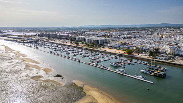 Harbour with small ships in Olhao, Algarve, Portugal, surrounded by buildings and land during daylight