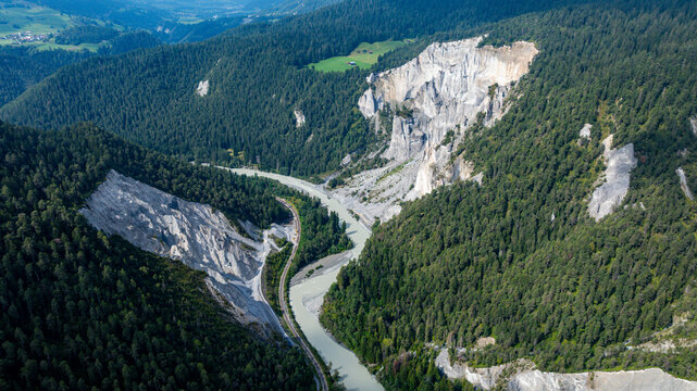 Aerial view captures the curves of the Rhein gorge surrounded by green hills and steep cliffs in Switzerland during daylight