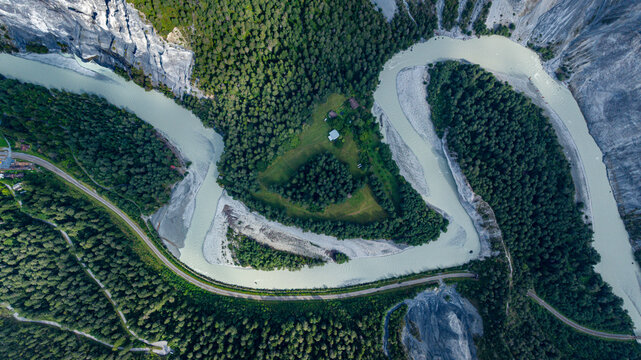 Aerial view shows the winding river and green landscape of Rhein gorge with forest and terrain in Switzerland under clear skies