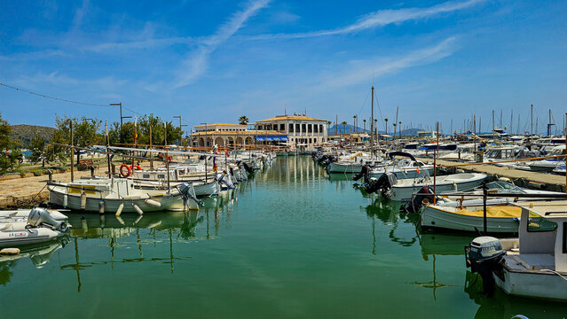 Boat harbour at Port de Pollenca features numerous boats lined up in clear water under blue skies in Mallorca, Spain
