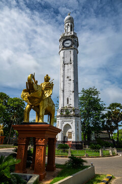 Clock tower stands tall in Jaffna as people pass by amidst greenery and blue skies in the Tamil region of Sri Lanka