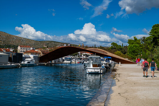 Modern bridge connects waterfront with historic town of Trogir in Croatia with boats in the harbor and people enjoying the scenery