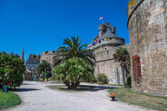 Visitors walk through the walled city of Saint-Malo with palm trees and historic architecture in Brittany, France
