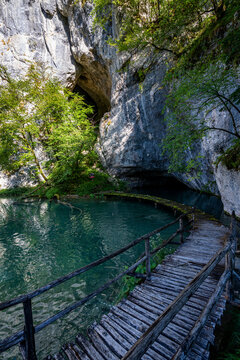 Explore the beauty of Plitvice Lakes National Park in Croatia with lush nature and clear waters near a cave entrance
