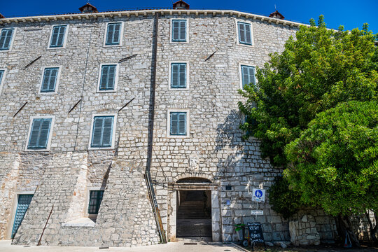 Exploring historic stone buildings in the old city of Sibenik, Croatia, under a clear blue sky