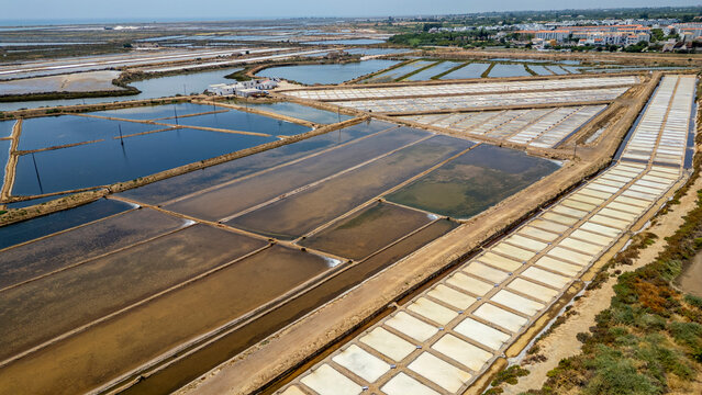Birds-eye view of saltpans showing lines of water and salt preparation in a coastal area located in Algarve, Portugal during bright daylight