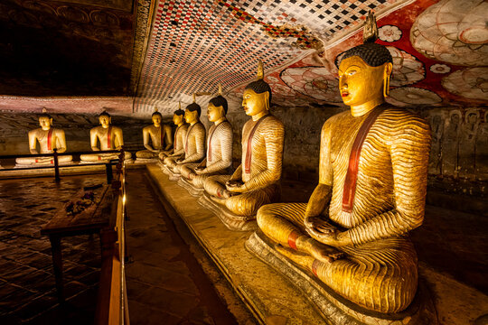 Buddha statues arranged in seated positions inside the cave temple in Dambulla reveal ancient artistry and cultural history in Central Sri Lanka