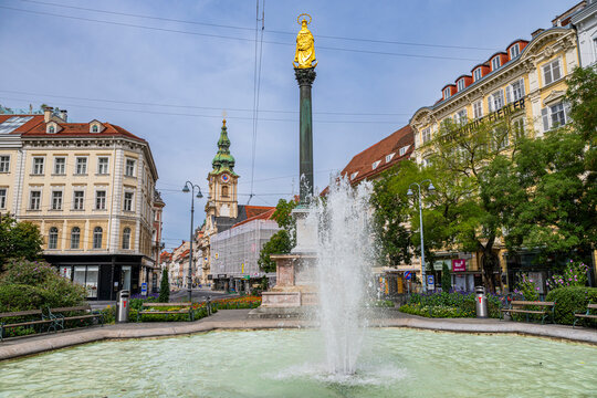 Fountain at downtown Graz featuring a statue and buildings on a sunny day in Austria