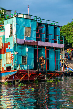 House boat floating on the Buriganga River with a person on board under a clear sky in Dhaka, Bangladesh