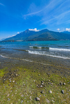 Lakeshore view of beach in Dongo by Lake Como with clear sky and distant mountains in Italy