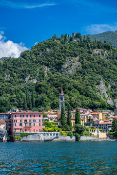 Varenna, a small town by Lake Como, Italy, presents colorful buildings and a hillside with trees and a tower