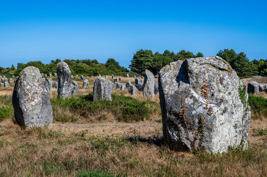 Historic stone alignment stands under clear blue sky in rural France near ancient ruins and nature