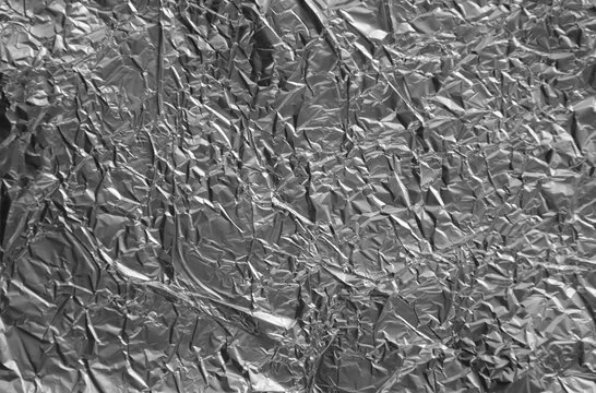 Processed collage of shiny metal silver gray foil crumpled packaging material texture