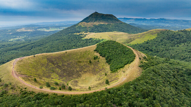 Volcanic domes rise above green fields in the Chaine de Puys, showcasing geological features in Central France