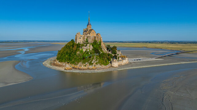View of Mont St. Michel surrounded by water at low tide in France showing the historic architecture and natural landscape