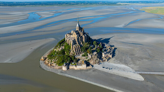 View of Mont St. Michel from above showing island, sand, and water in France during a clear day