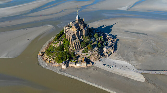 View of Mont St. Michel, a UNESCO site in France, showcasing its architecture and surrounding bay area at low tide