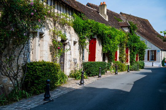 Charming buildings line a narrow street in Provins, with flowers and greenery adorning their facades