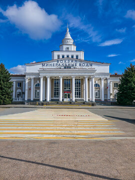 Historic railway station building in a spa town with blue skies and green trees