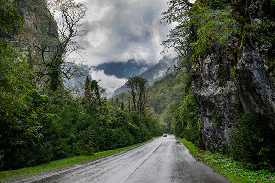 Road through dramatic mountains and lush greenery near Ritsa National Park in Russia