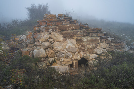 Visibility limited in fog at Lezgor Necropolis in North Ossetia, Russia with stone structures partially obscured