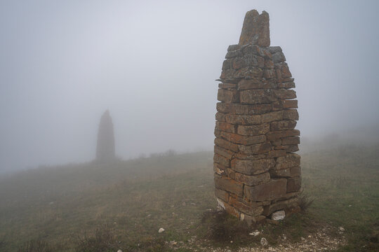 View of ancient stone structures shrouded in fog with a backdrop of hidden landscape in North Ossetia, Russia
