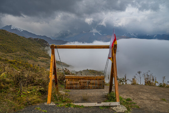 Swing placed in mountain passes of Caucasus offers view of fog and clouds in North Ossetia, Russia during overcast weather