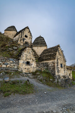 Ancient burial structures stand on a hillside in Dargavs, representing historical significance in North Ossetia, Russia