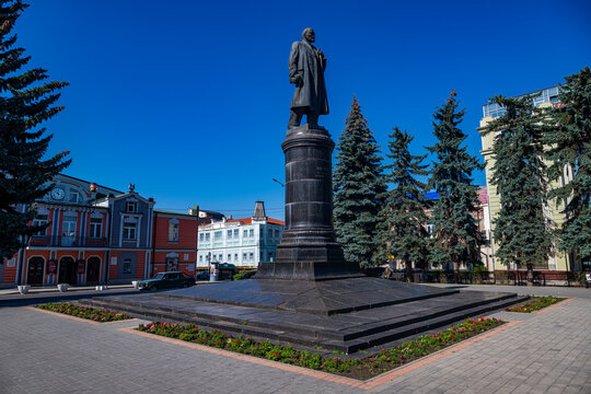 Historical statue of Lenin stands in Vladikavkaz surrounded by buildings and trees in a sunny day