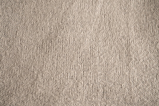 Knit pattern in beige wool fabric. Fine woven cotton texture for a decorative background. Close-up. Top view.