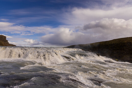 Gullfoss waterfalls upper cascade in South Iceland with rushing water and a cloudy sky