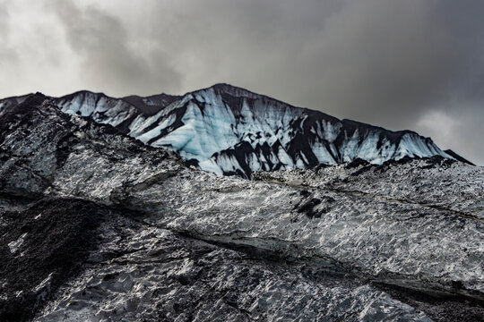 Dark ash and ice layers show volcanic activity on Katla glacier under gray clouds in Iceland