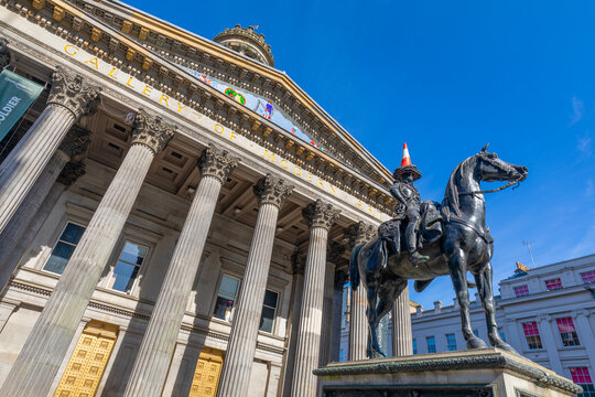 Statue of Duke of Wellington with a traffic cone on its head outside Glasgow Museum of Modern Art in Scotland during daytime