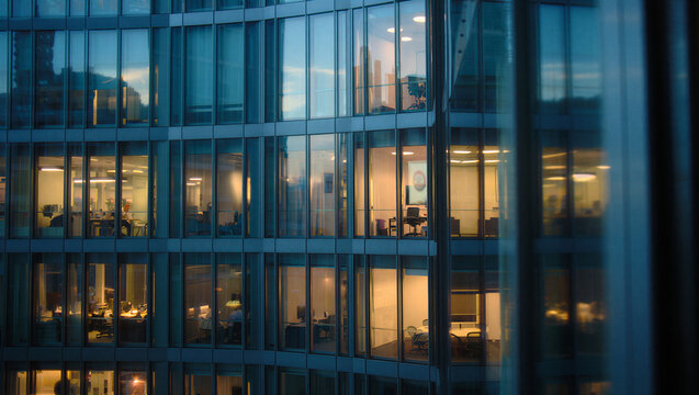 Close up view of modern office building glass facade with people working late real estate building